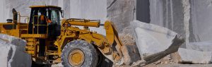 yellow earth mover carrying large rock in quarry